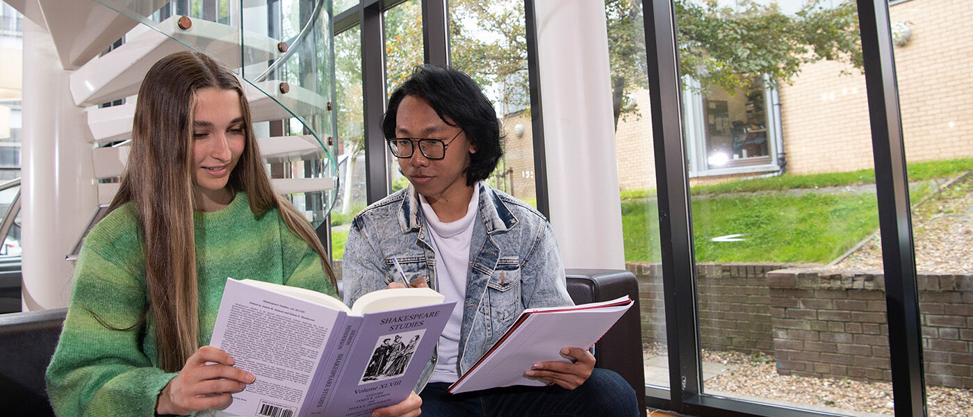 Two students discussing a literature studies book