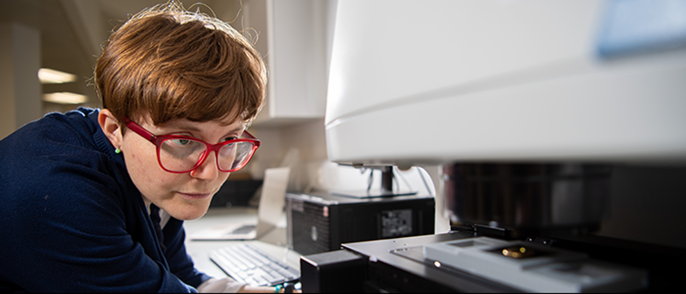 A woman examining an ancient coin under a microscope