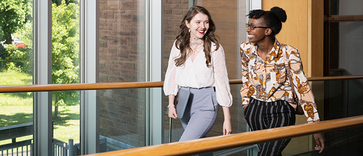 Students walking through a hallway in front of a window at the University of Glasgow Dumfries campus
