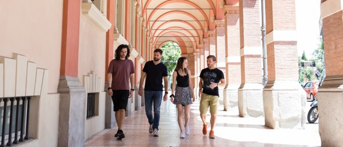 Four students walking side by side in Bologna