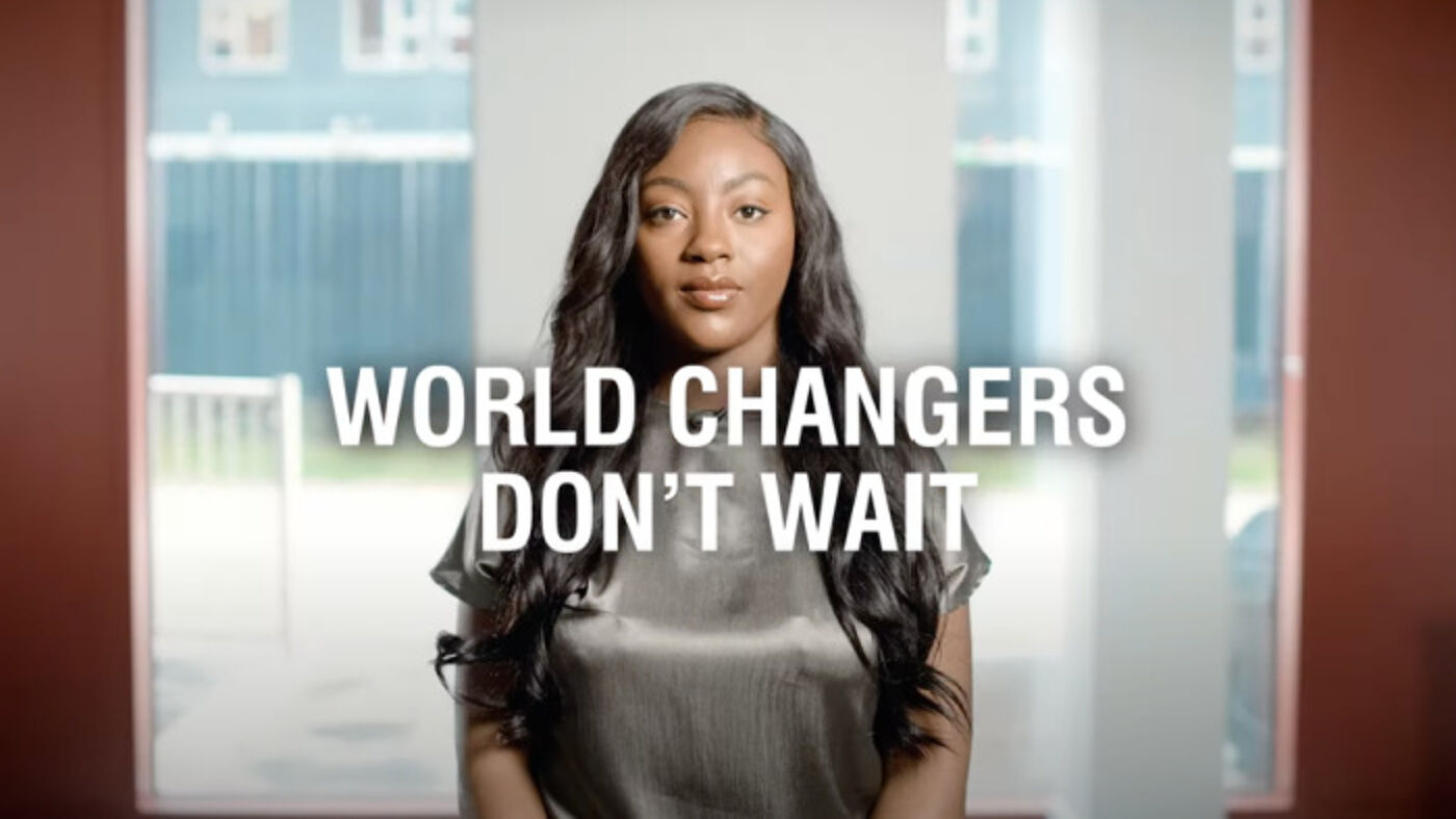 Screenshot from brand video showing an student behind the words 'World changers don't wait'.