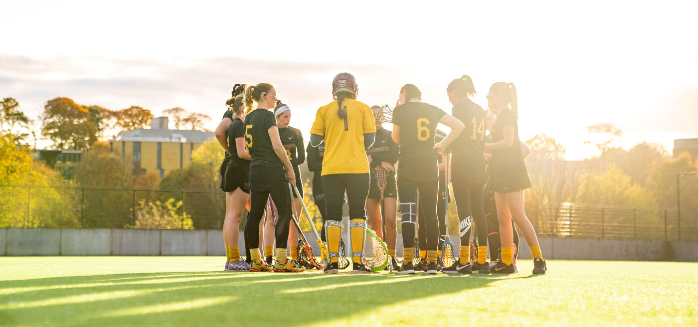 Womens Lacrosse team standing in group on pitch