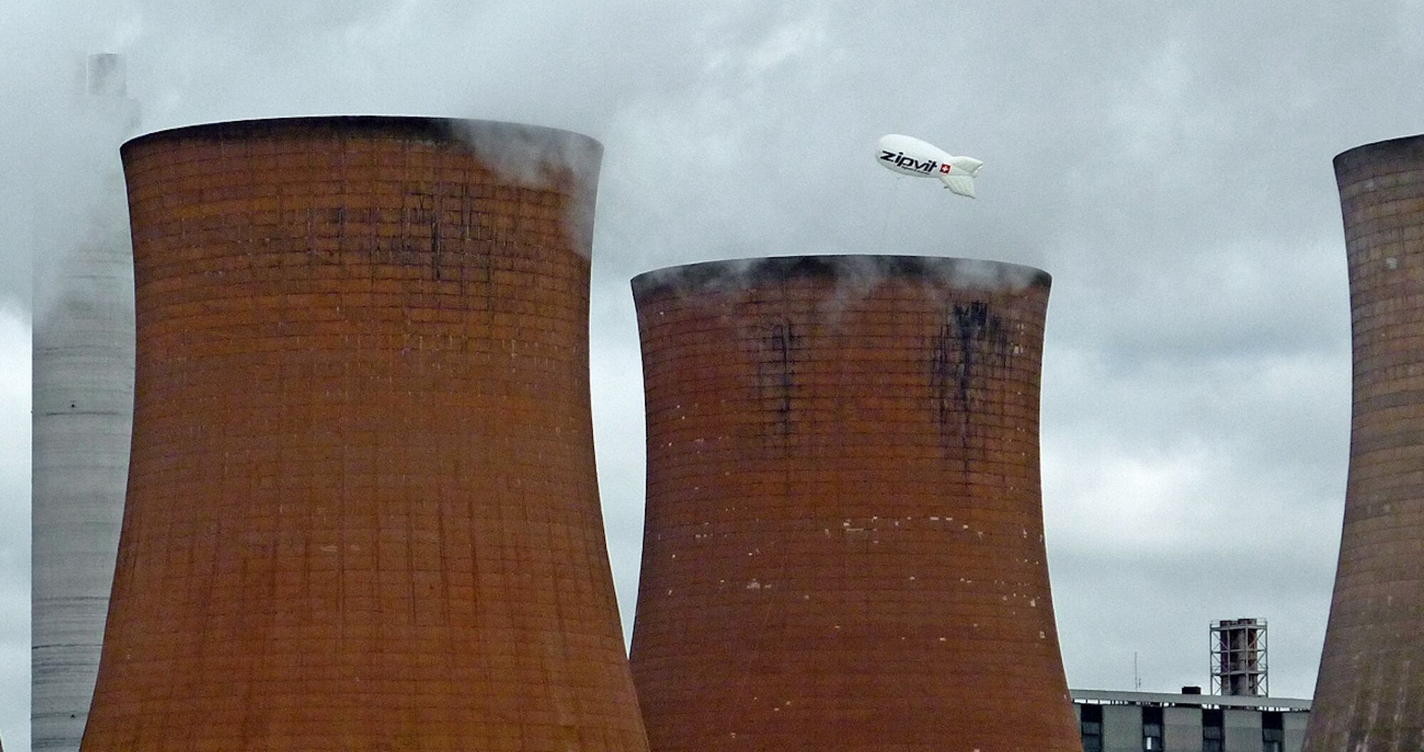 Three tall, curved brick towers with steam coming out of the top, at Rugeley power station