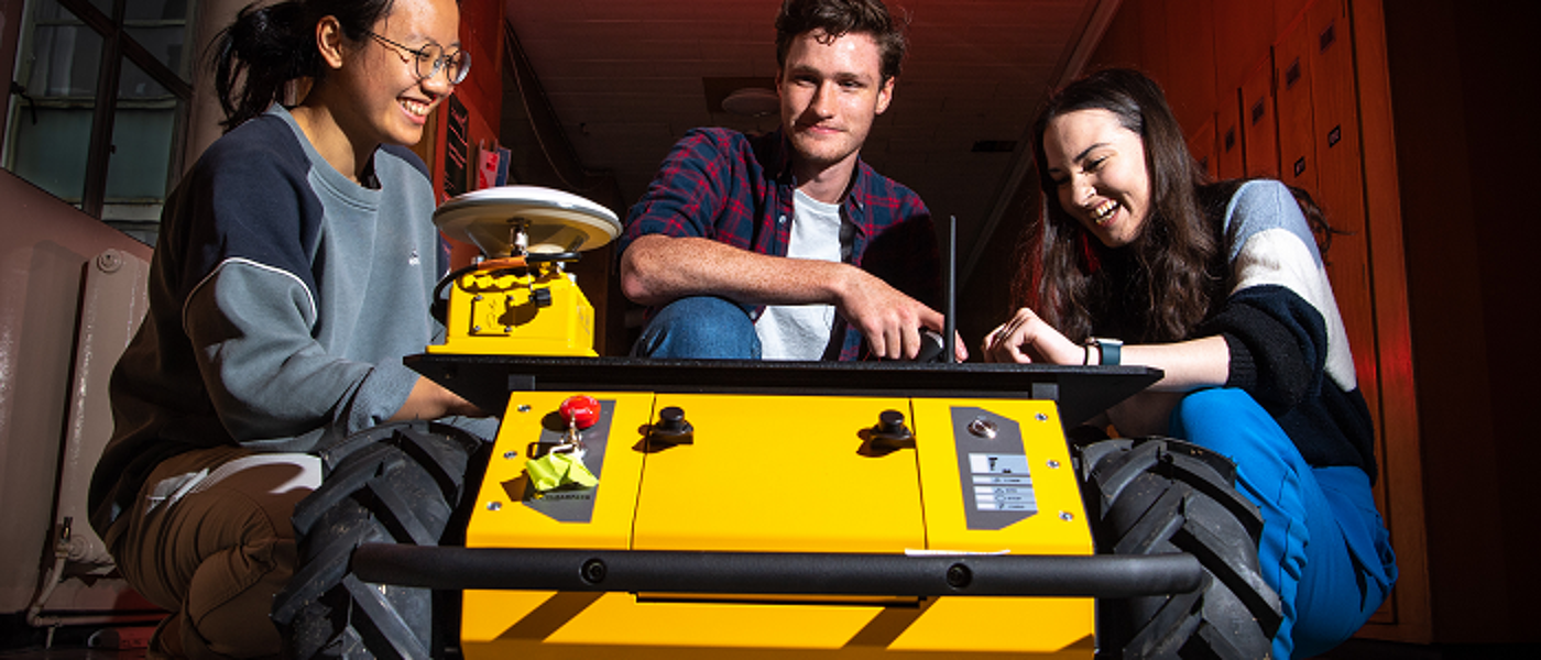 Three students with yellow robot vehicle