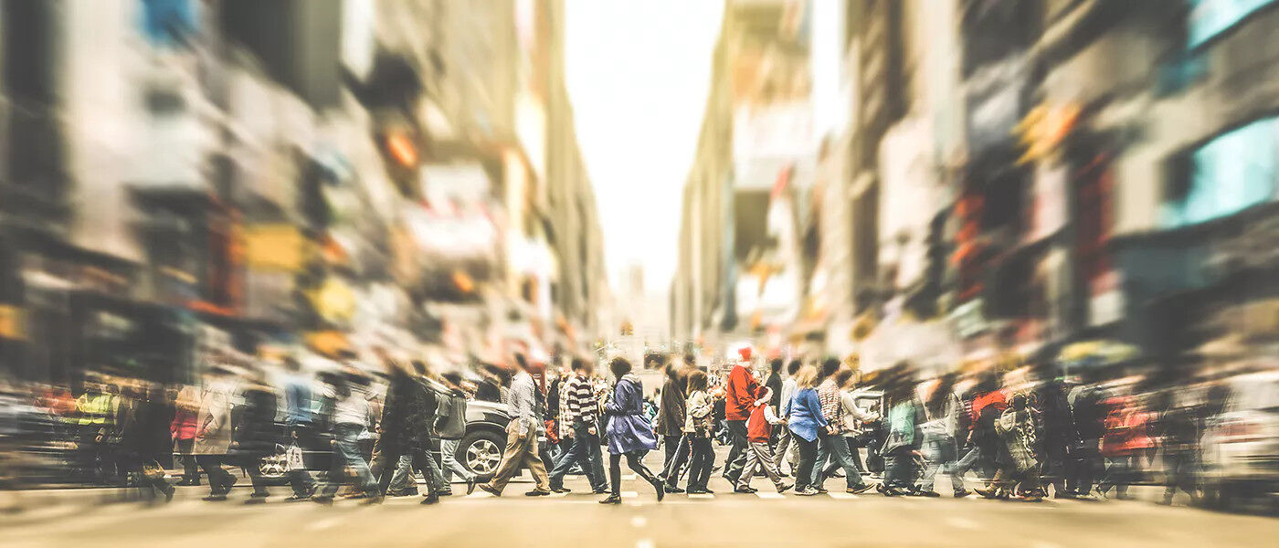 Crowds crossing a busy urban street