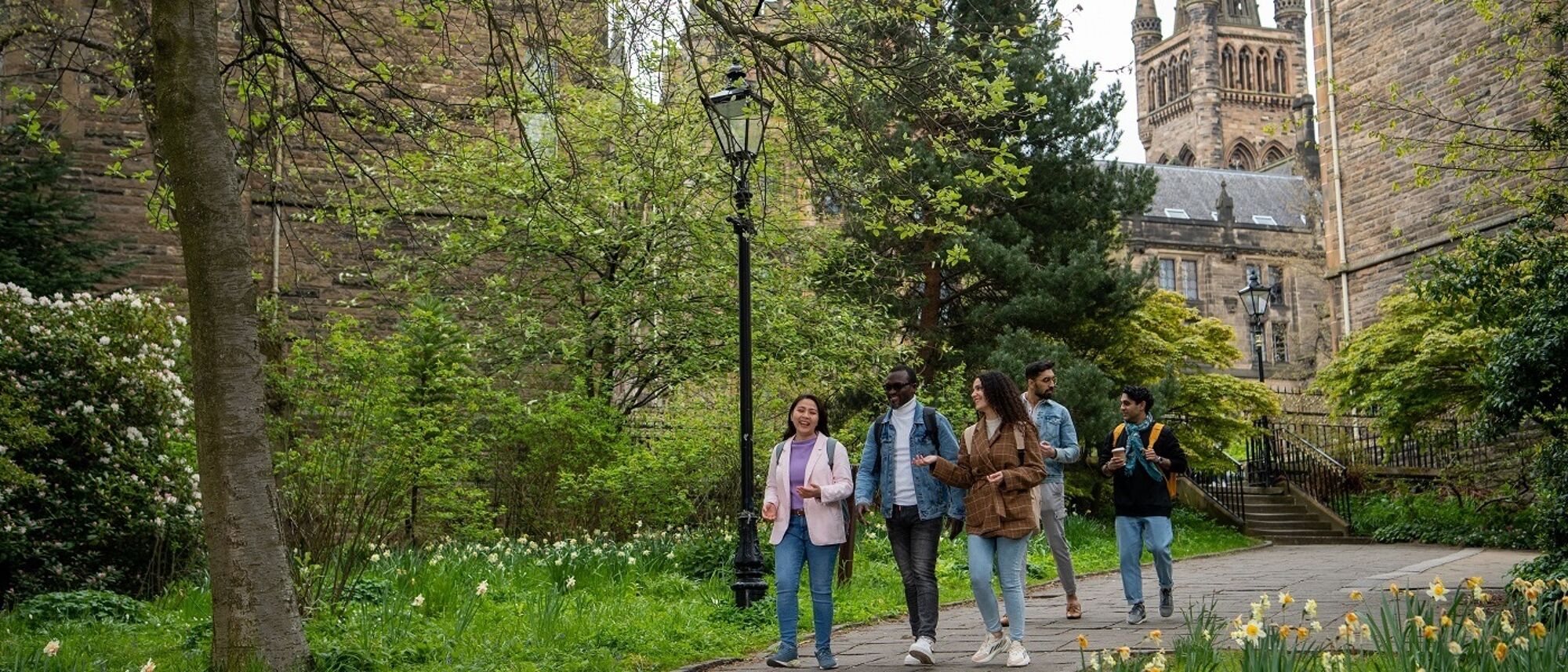 Students walking through park with University building in background