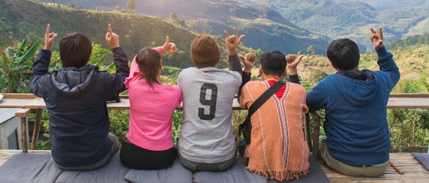 Rear view of group friends  sitting together on mountain view relaxing