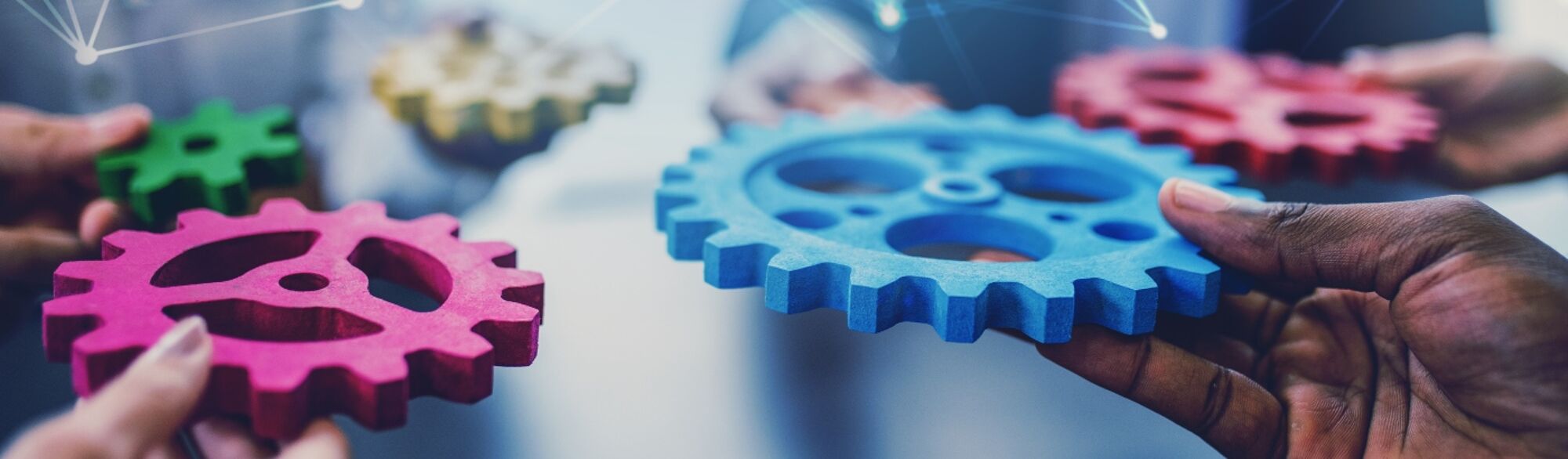 People holding bright coloured cogs, teamwork concept