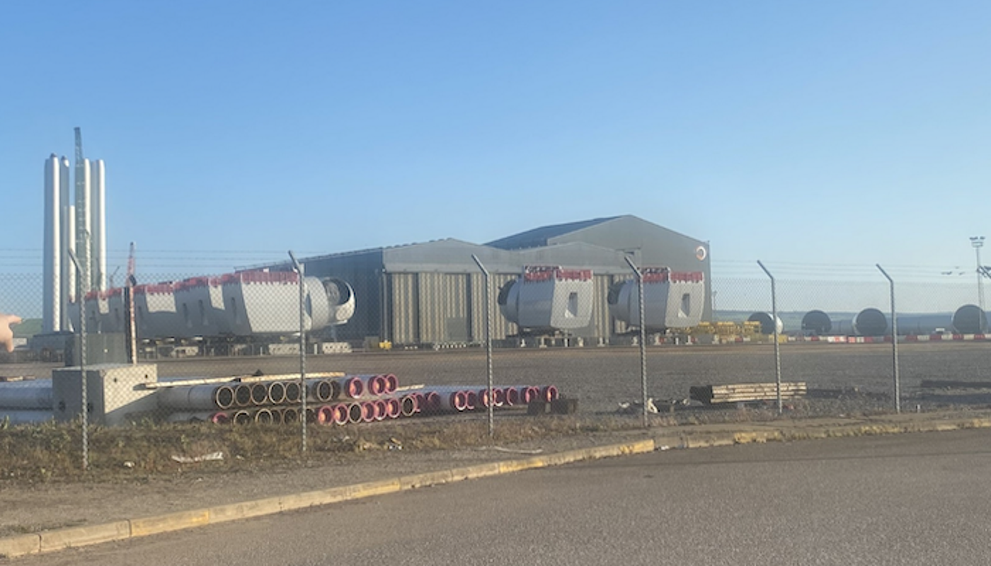 Nigg yard 1400 x 740 View of a construction yard with a shed and large pieces of equipment against a blue sky. Photo credit: Ewan Gibbs
