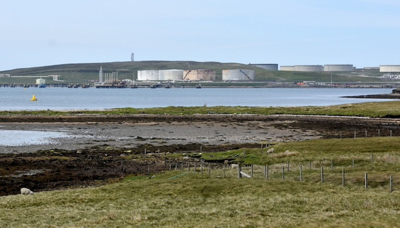 A view of Sullom Voe oil terminal with industrial building on the shore of an inlet of the sea. Photo credit: James Stringer, Flickr https://www.flickr.com/photos/jamesstringer/48068245541/