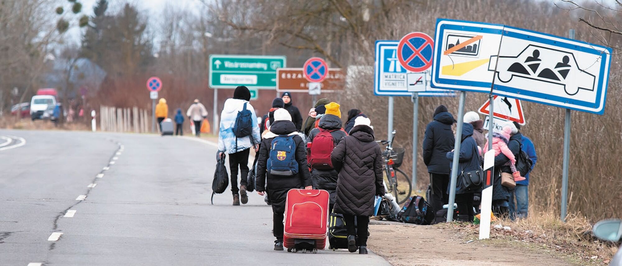 Migrants walking along a road with luggage