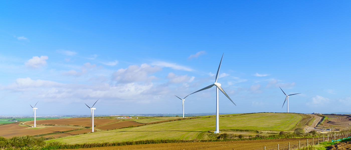 Windmills at windfarm with fields and blue skies