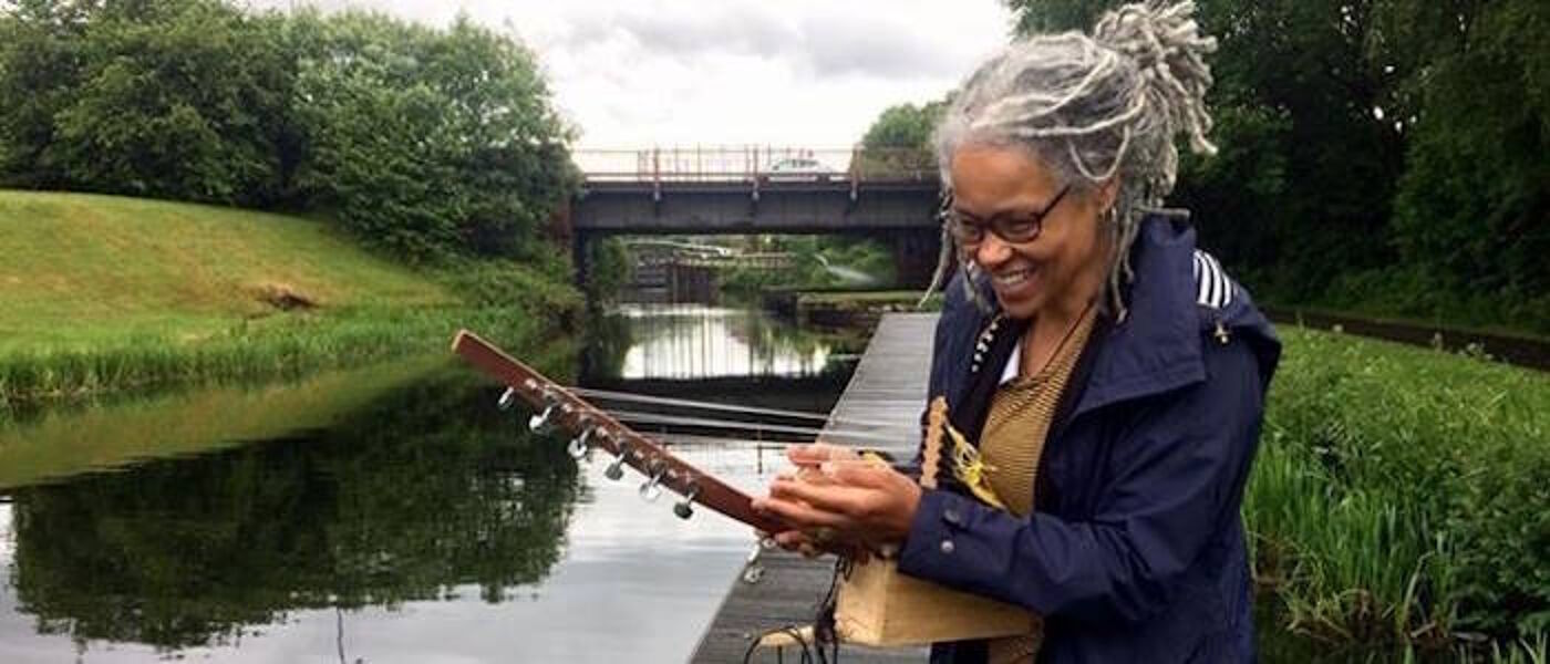 Edugie Clare Robertson playing a string instrument next to a canal