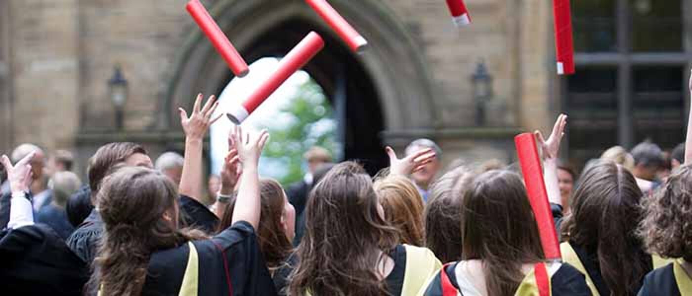 Image of students at graduation throwing red scrolls in the air