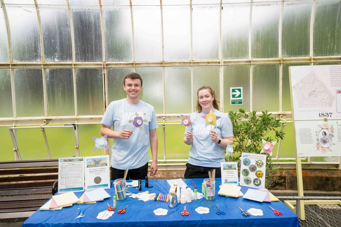 Two GSF volunteers standing behind an activity table holding paper flowers.
