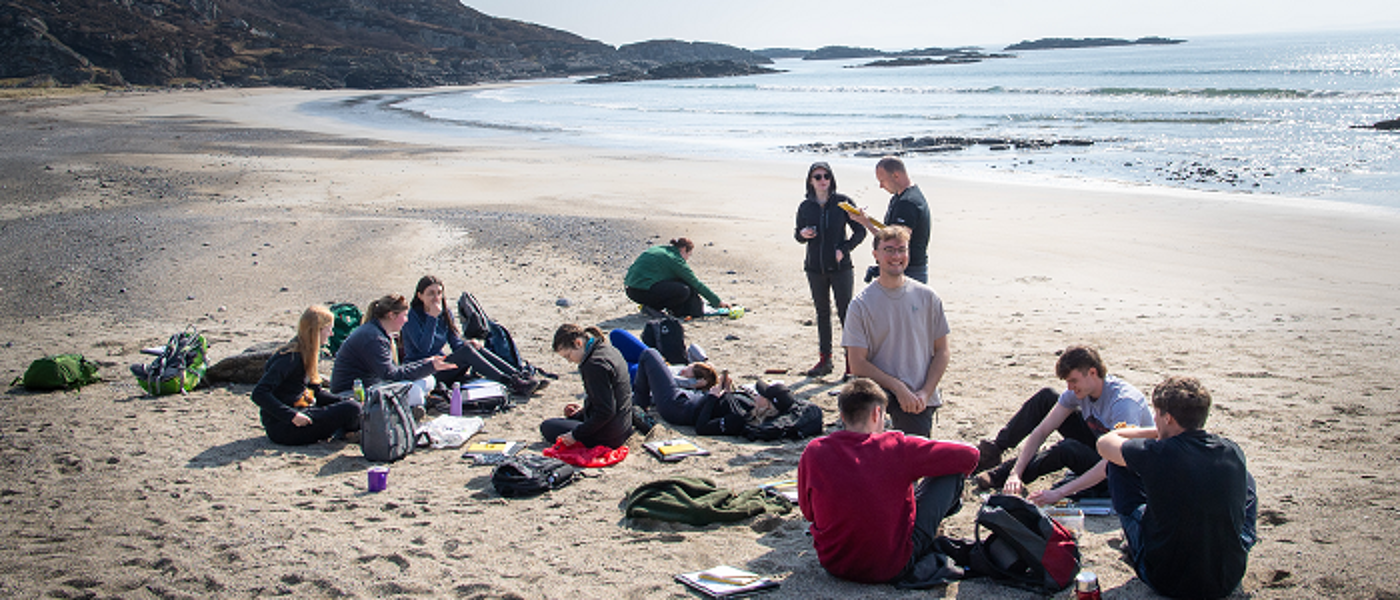 Students sitting on beach during field trip