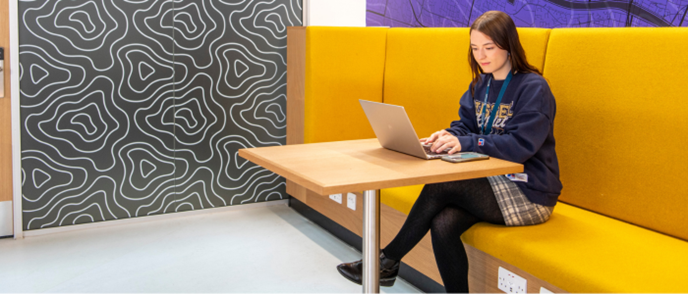A staff member sitting at a table with a laptop