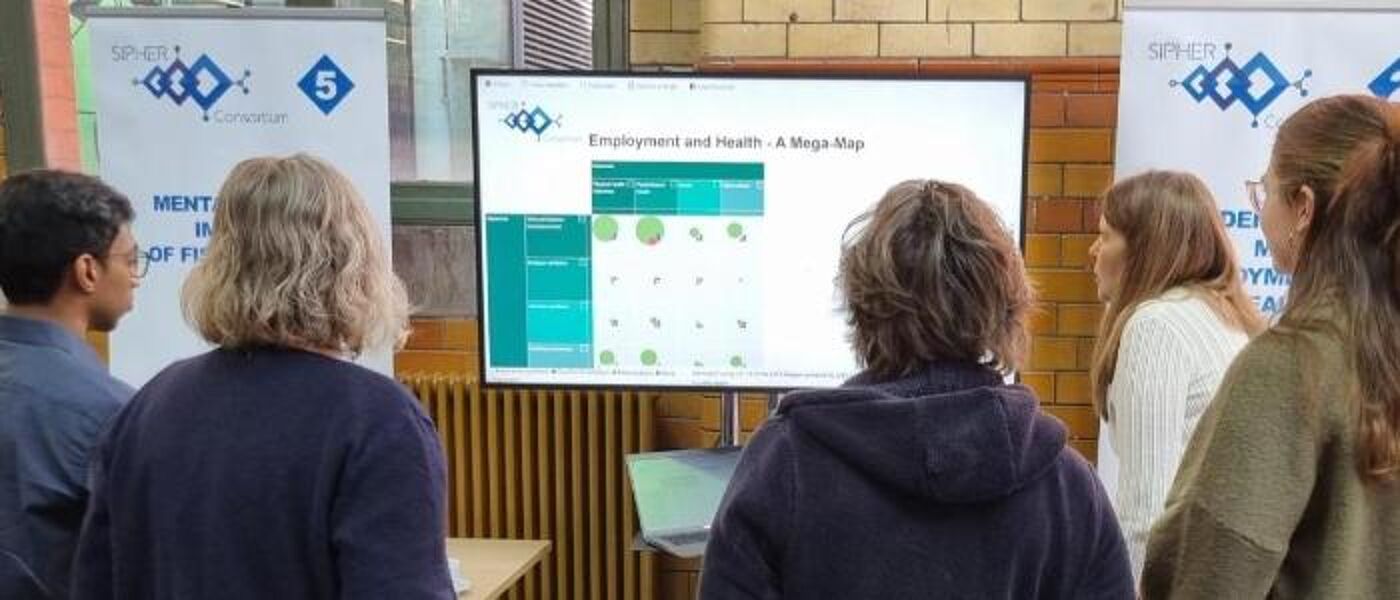 Group standing facing away to look at stand display at SIPHER Showcase event  