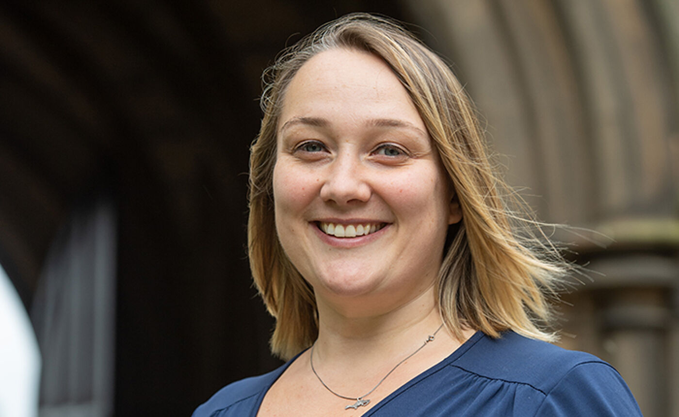 Professor Kathleen Riach standing in cloisters at the University of Glasgow