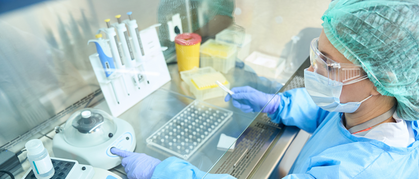 Researcher in scrubs and mask working with biomaterials