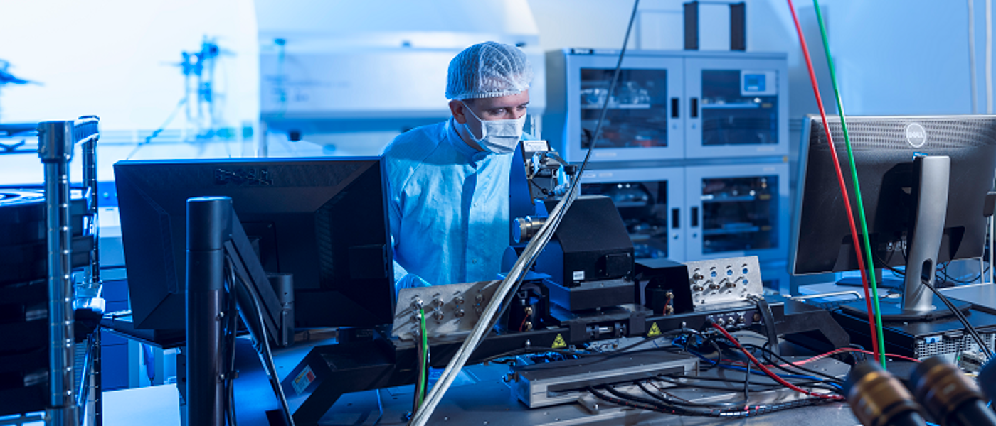 Researcher wearing hairnet and lab coat conducting physics research
