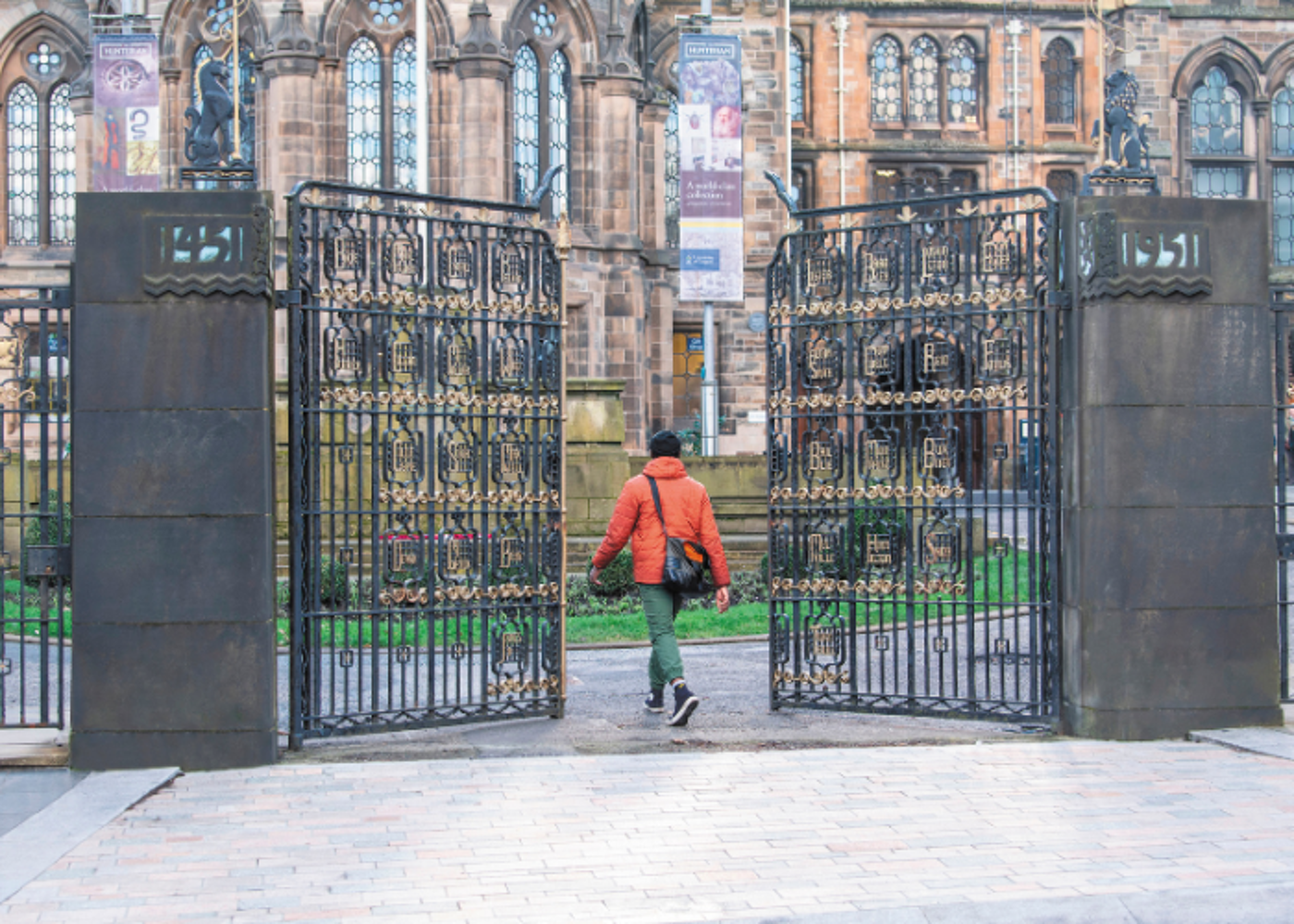 Student walking through the Memorial Gates at the University of Glasgow