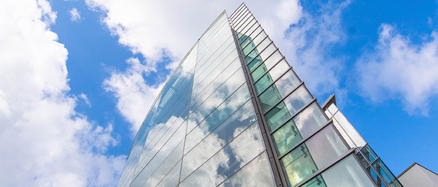 The glass front of the Wolfson Medical School Building with clouds