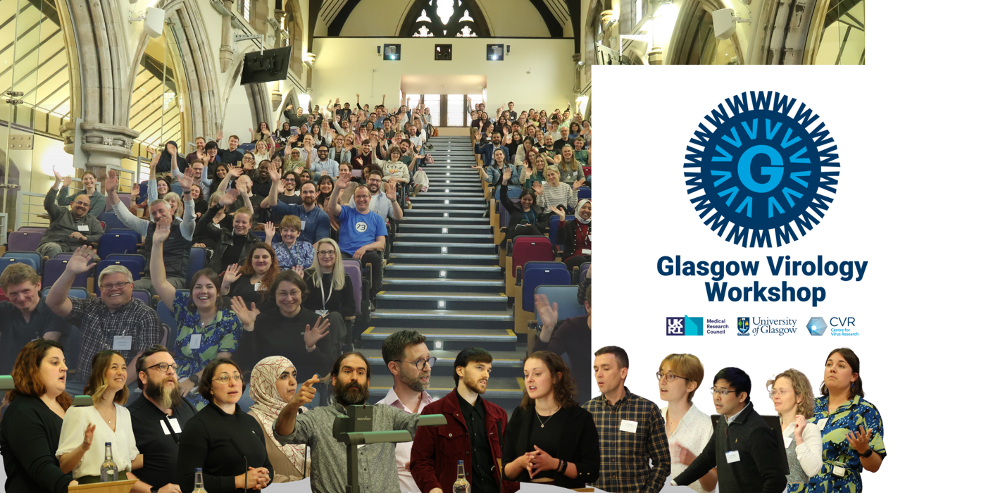 The image shows a large group of people seated in an auditorium attending an event. Some individuals are standing at the front. On the right side, there is a banner displaying the text