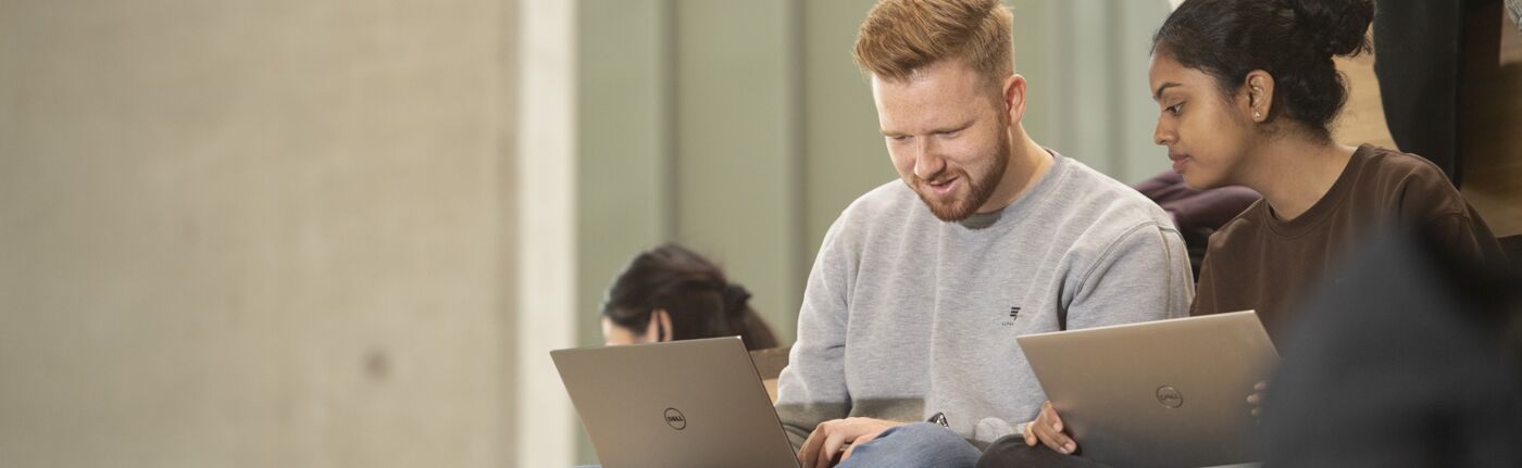 students sitting, working on laptops