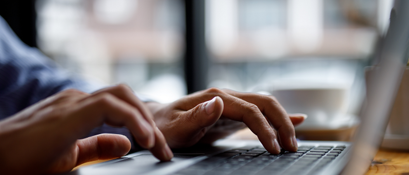 Close up of hands typing on a laptop keyboard