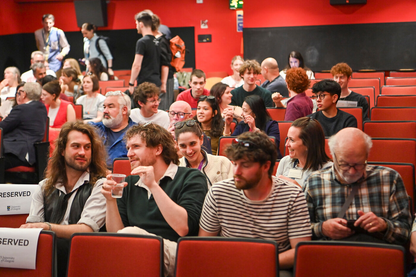 a large group of staff, students and participants sitting in the Andrew Stewart Cinema speaking