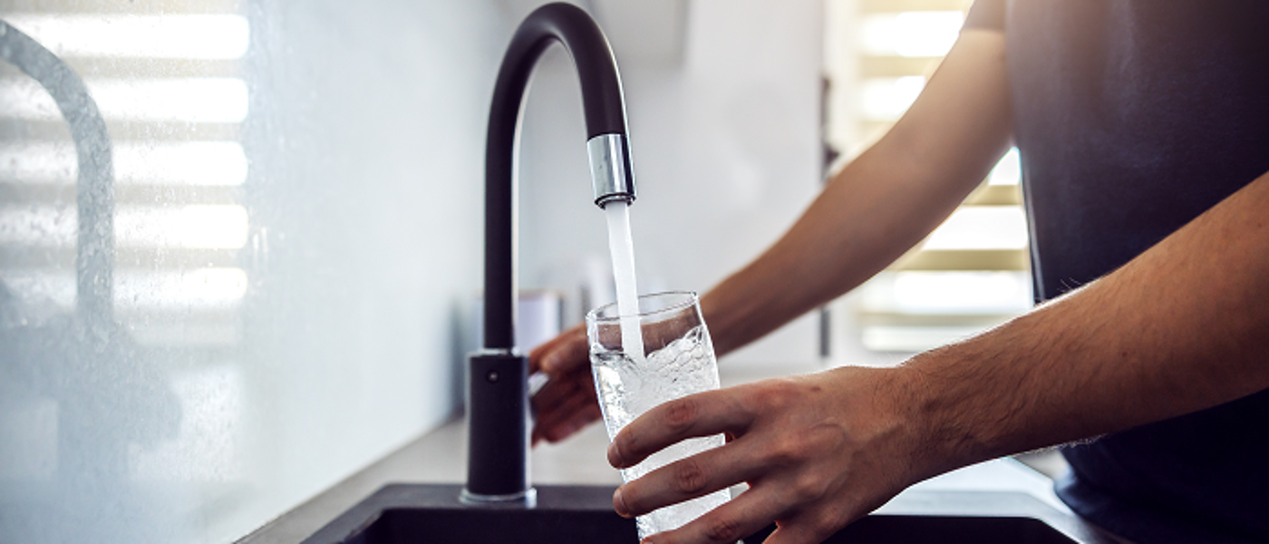 Hands holding glass under tap