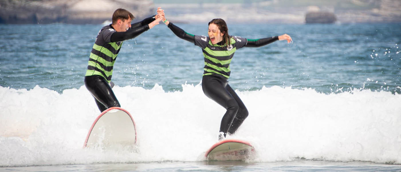 Two students on surfboards high-fiving