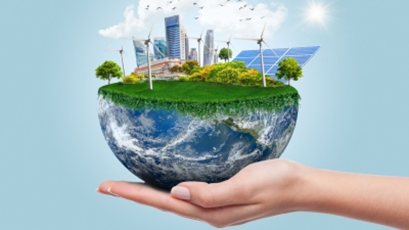 A hand holding a half Earth and renewable energy on top