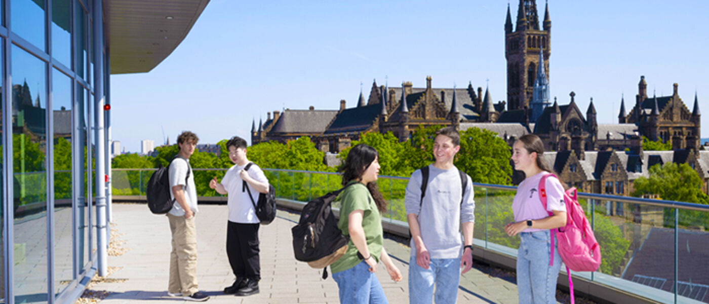 Students on the balcony of the modern JMSLH building with historic buildings in the background