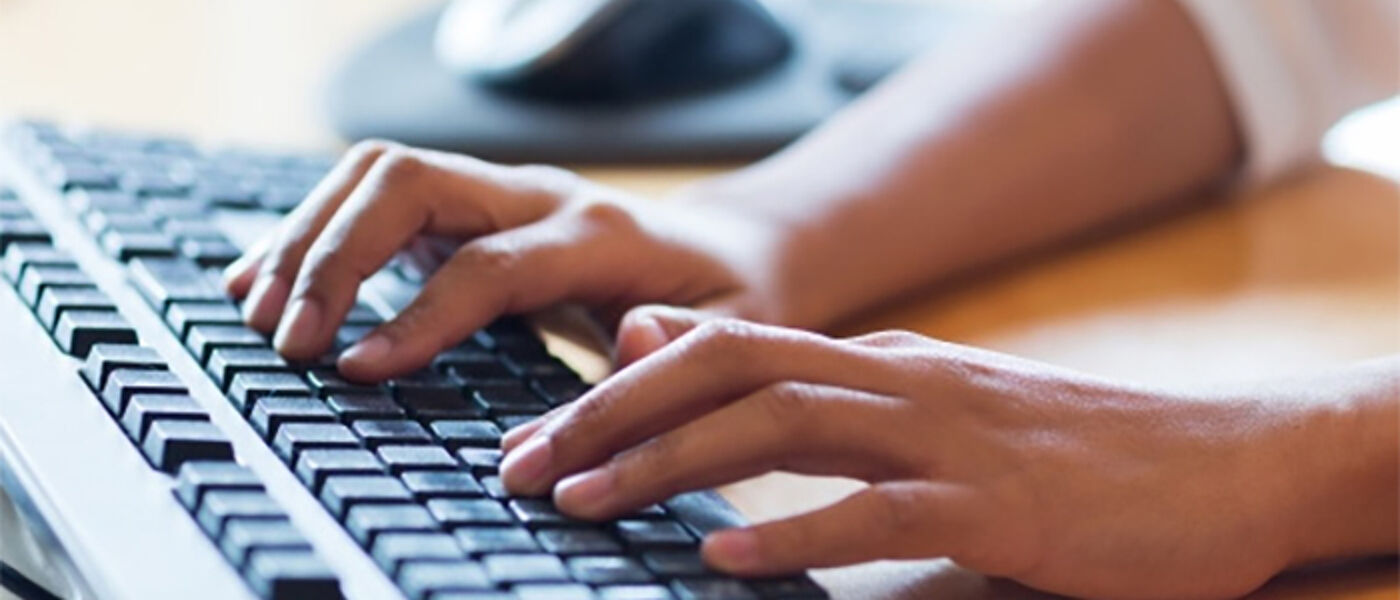Two hands typing on a keyboard