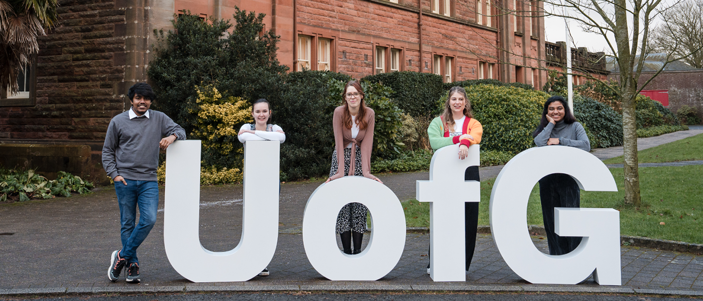 Group of students at a UofG sign