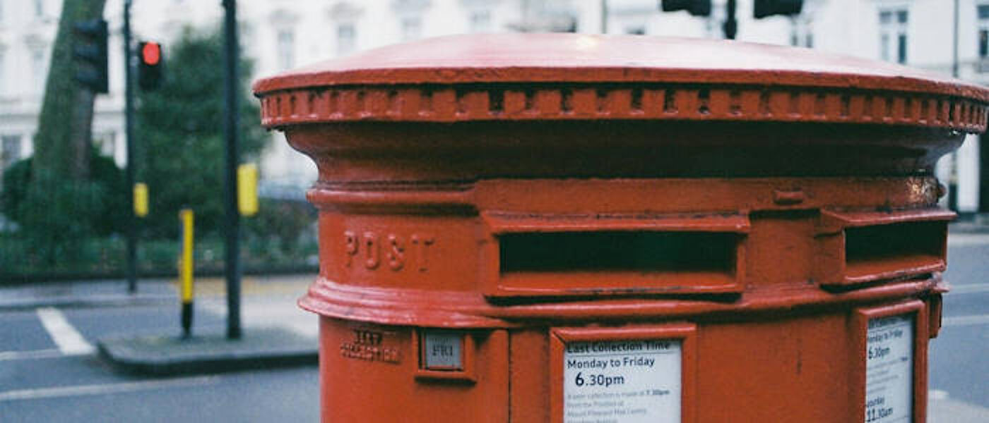 A close-up shot of the letter opening on a red pillar style post box, the word 