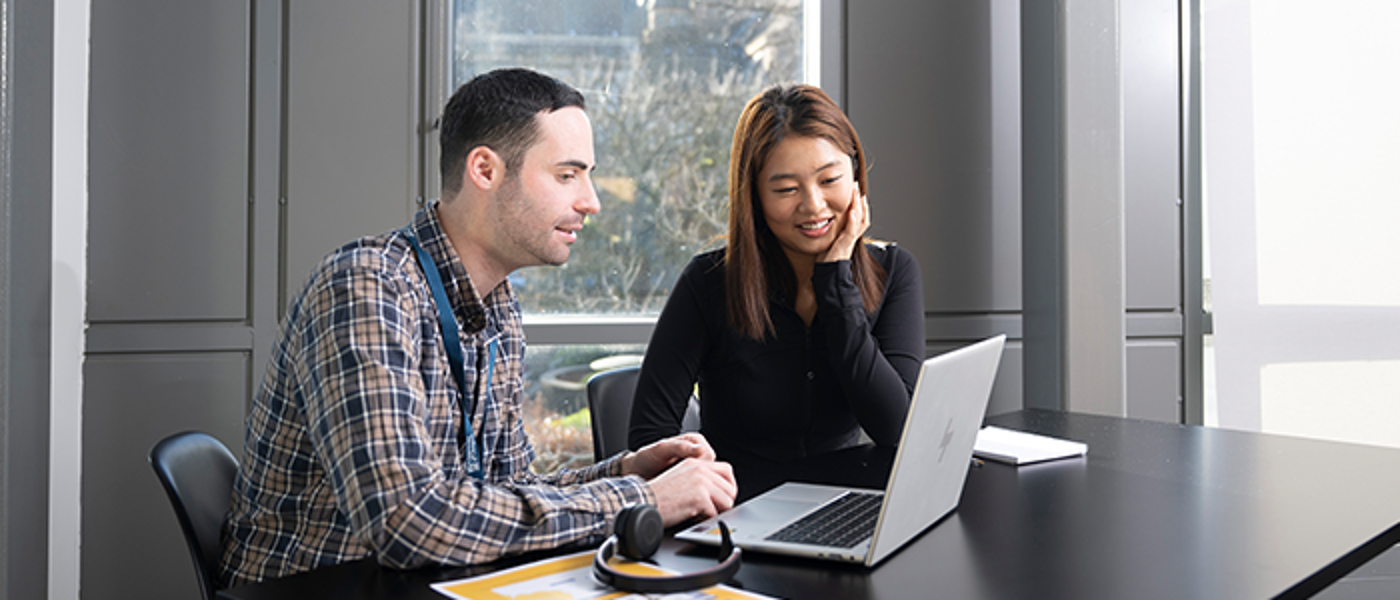 A member of staff speaking with a student at desk