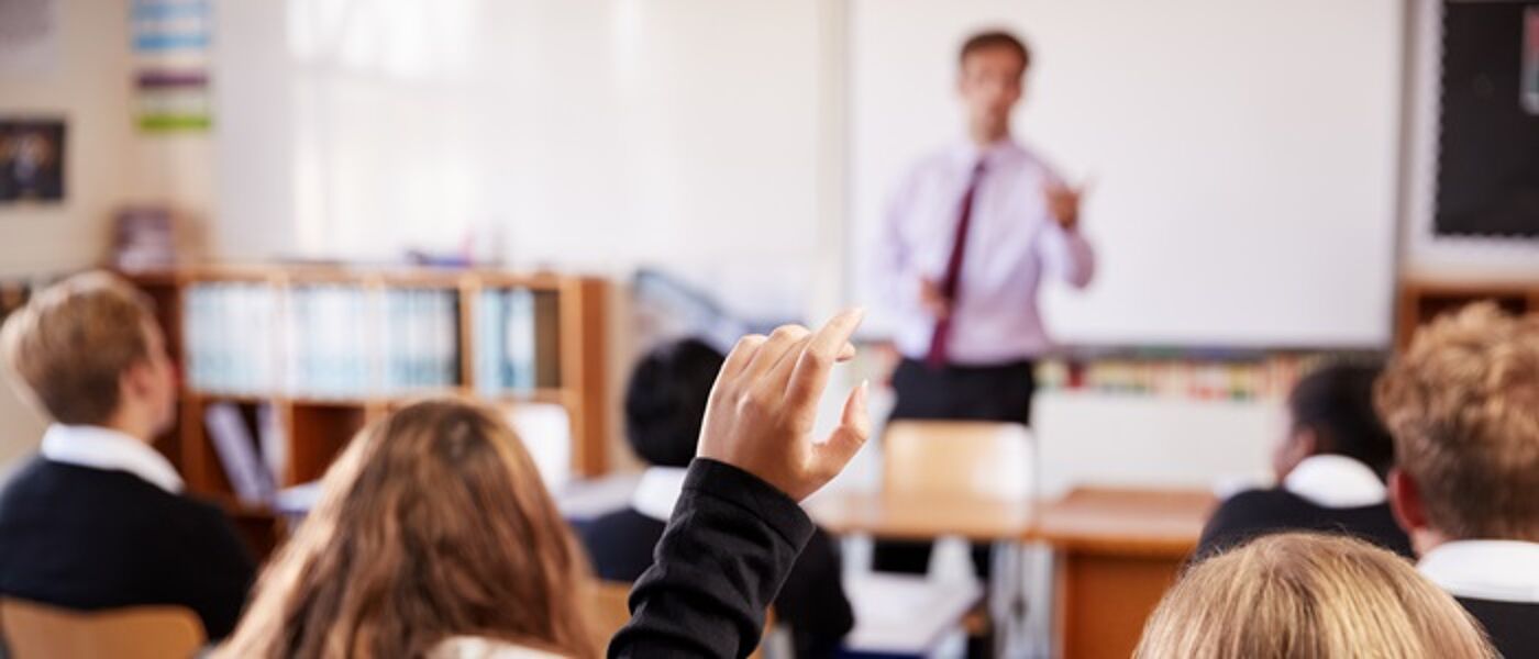 School pupils in a classroom with a male teacher at the front of the class