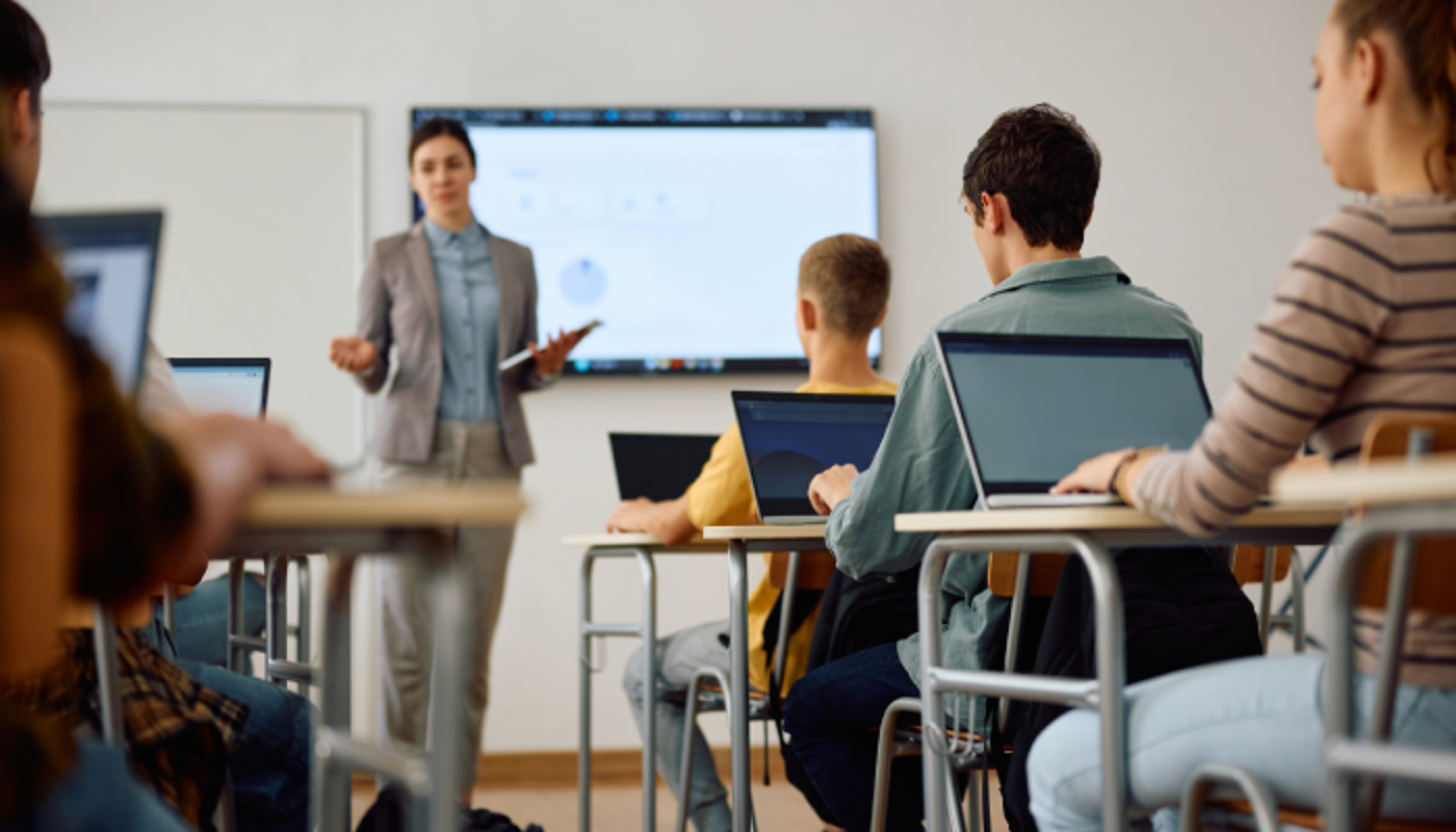 High school student and his classmates learning computer coding on a laptops in the classroom.