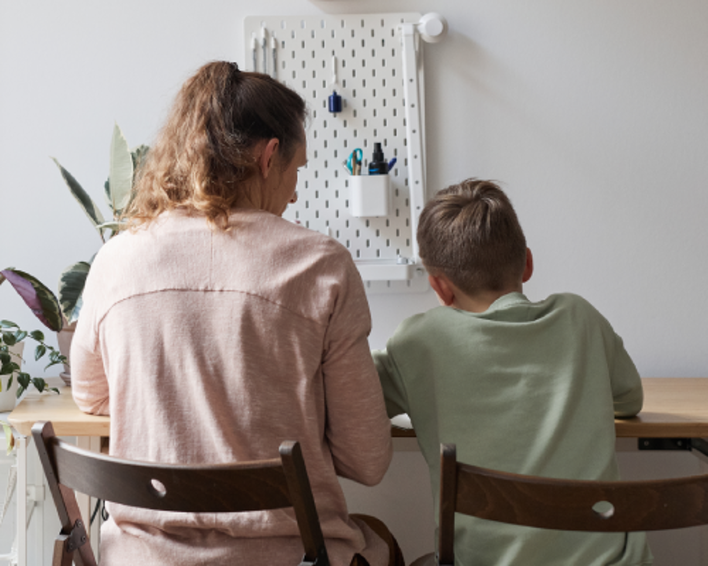 Back view portrait of caring single mother helping son doing homework in cozy home interior, copy space