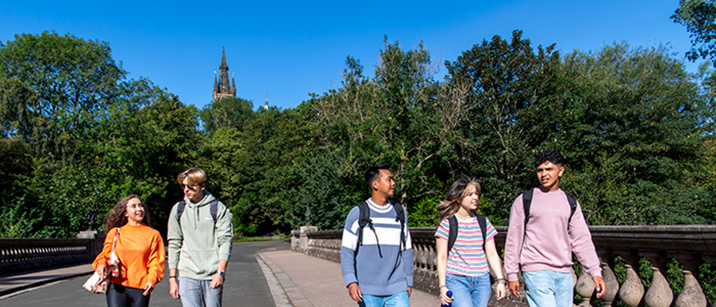 students walking through the park with main building in background