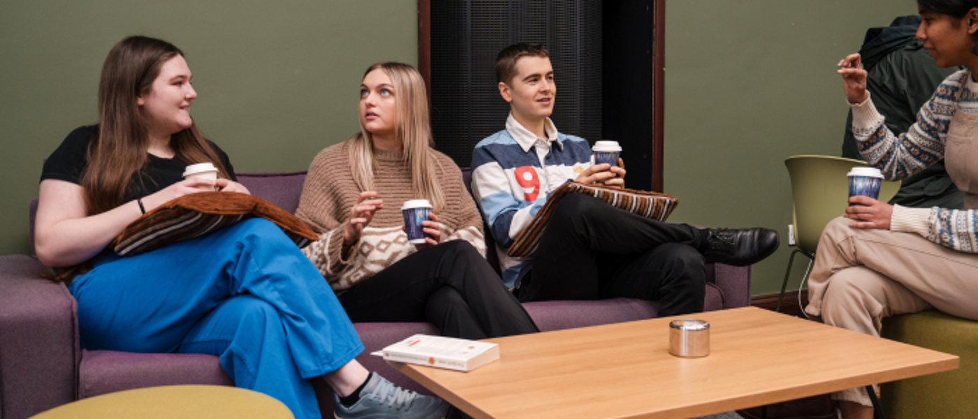 Four students sitting around a table talking to each other