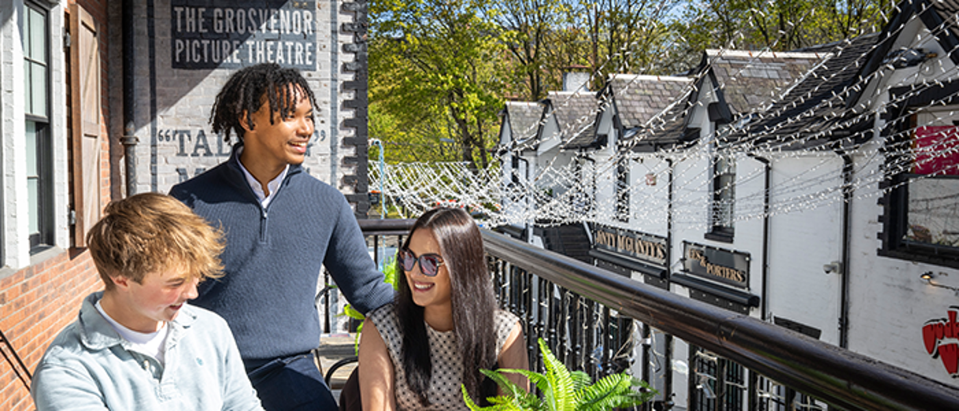 Three students on the balcony of the Grosvenor Picture Theatre smiling and chatting