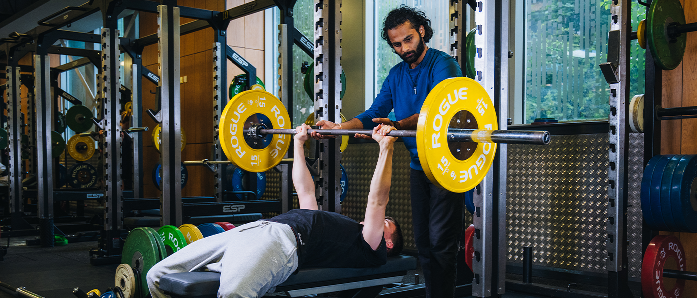 student spotting another student bench-pressing
