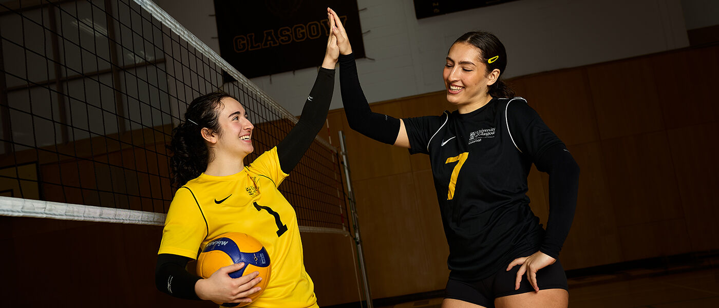 two female volleyball players high-fiving in the Sports Hall