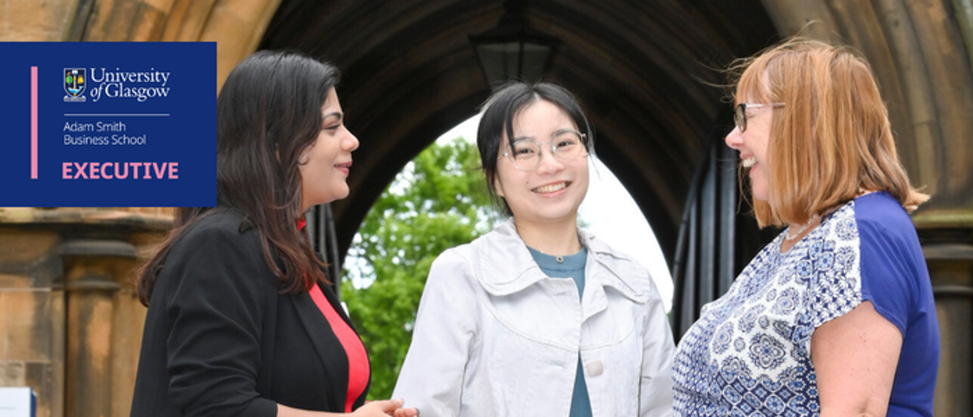 an image of 3 women in conversation. the centre women is smiling directly at the camera while the other two look at eachother in conversation.