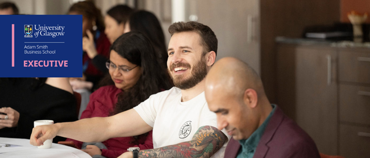 Ai Readiness executive education attendee laughs, engaged in the academics delivery while others take notes happily