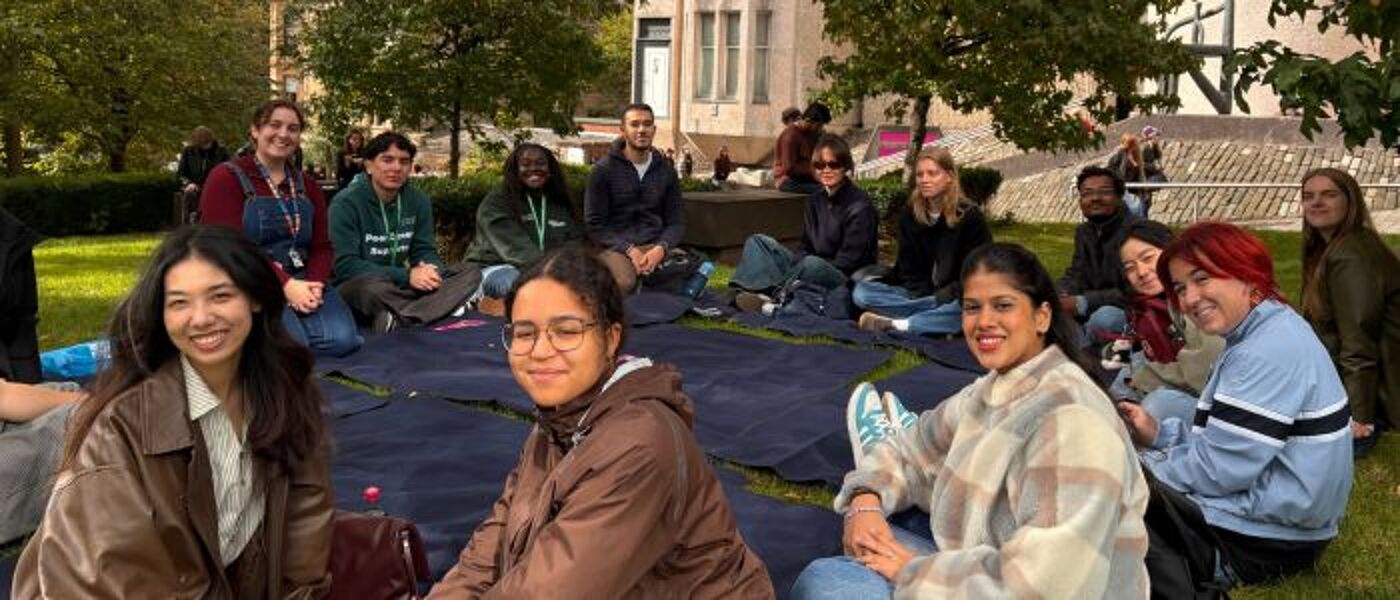 a group of students sitting in a circle on picnic blankets facing the camera
